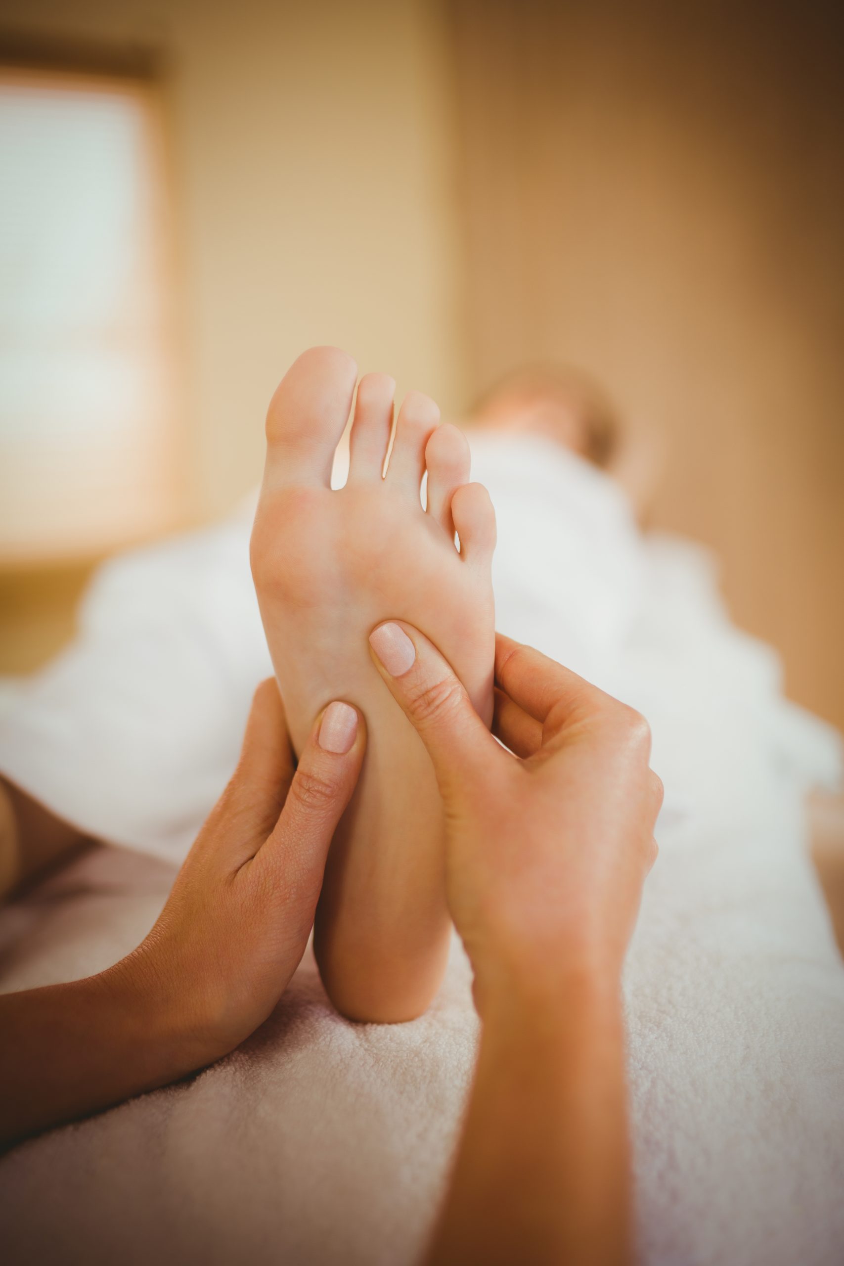 Réflexologie plantaire : mains qui massent la voûte du pied pendant une séance